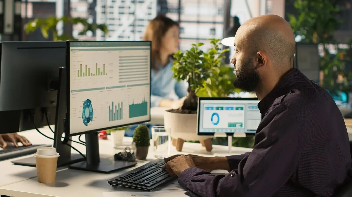 Сотрудник редактирует документы на настольном компьютере за офисным столом.